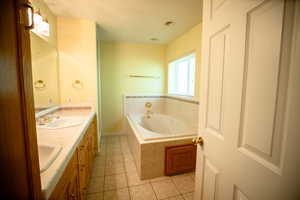 Bathroom featuring light tile patterned flooring, a garden tub, and double vanity
