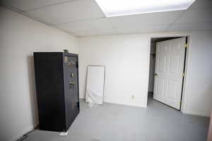 Unfurnished bedroom featuring concrete flooring and a drop ceiling