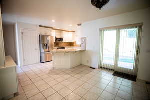 Kitchen featuring light tile patterned floors, appliances with stainless steel finishes, a peninsula, a breakfast bar area, and recessed lighting