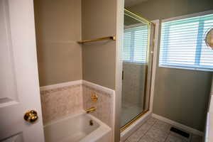 Full bath featuring a bath, light tile patterned flooring, healthy amount of natural light, and a stall shower