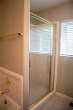Full bathroom with light tile patterned floors, a stall shower, and a bath