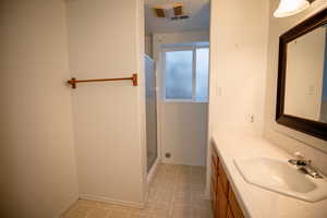 Bathroom featuring vanity, a shower stall, and light flooring