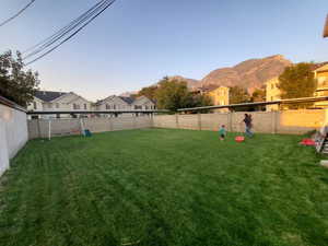 Fenced backyard featuring a residential view and a playground