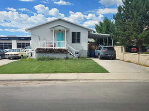 View of front of property with driveway, a front lawn, an attached carport, and covered porch