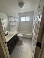 Full bath featuring bathing tub / shower combination, vanity, light tile patterned flooring, and a textured ceiling