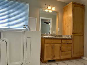 Full bath featuring vanity, light tile patterned floors,  and a tub