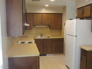 Kitchen with freestanding refrigerator, light countertops, recessed lighting, and brown cabinets
