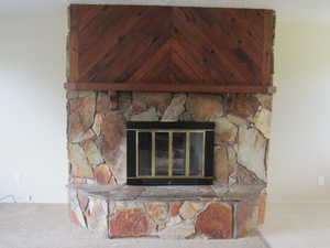 Detailed view of a stone fireplace and carpet flooring
