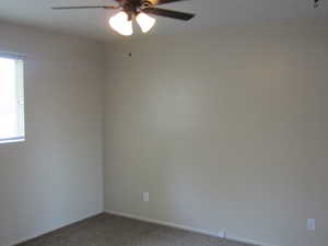 Unfurnished room featuring carpet and a ceiling fan