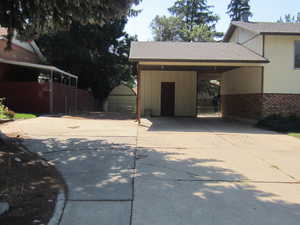 Garage featuring concrete driveway and a carport
