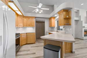 Kitchen with white appliances, light countertops, light wood-style flooring, light brown cabinetry, and recessed lighting