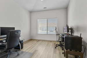 Home office with light wood finished floors and a textured ceiling