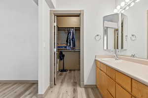 Bathroom with vanity, light wood-style flooring, and a spacious closet