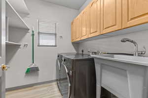 Laundry area featuring light wood finished floors, washing machine and dryer, and cabinet space