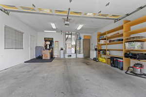 Garage with gas water heater, heating unit, and a garage door opener