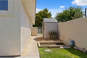 View of side of property with stucco siding, a shed, and a gate