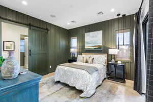 Bedroom featuring a barn door, wood finished floors, multiple windows, recessed lighting, and wood walls
