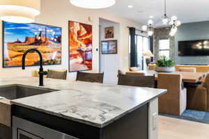 Kitchen featuring decorative light fixtures, open floor plan, light stone countertops, a chandelier, and light wood-style floors