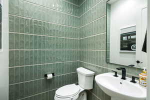 Bathroom featuring toilet and tile walls