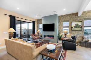 Living area featuring a fireplace, plenty of natural light, light wood-style flooring, recessed lighting, and beam ceiling