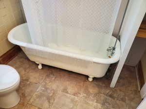 Full bath featuring a freestanding tub, tile patterned flooring, and tile walls