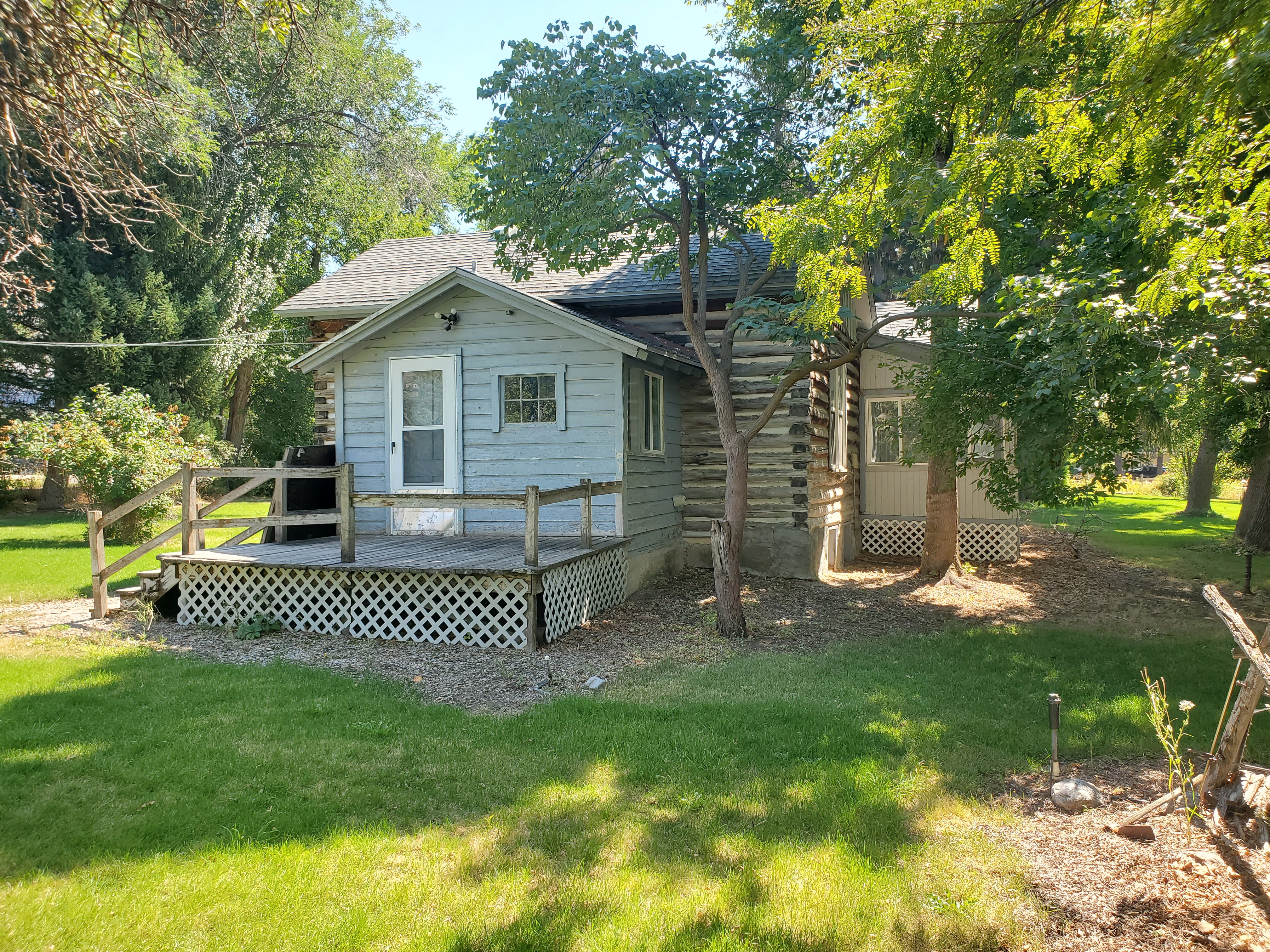 Rear view of property with a deck, a yard, and roof with shingles