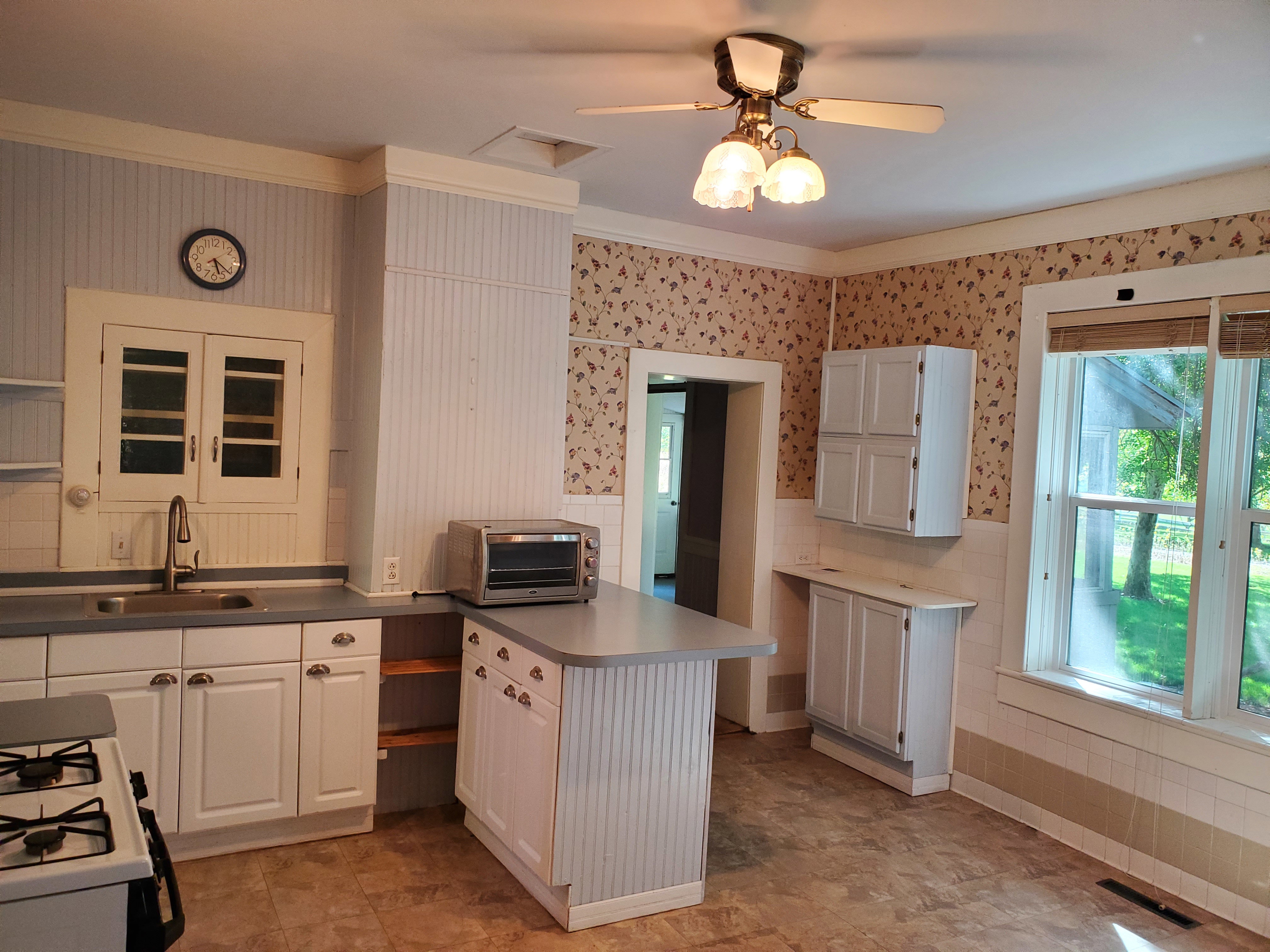 Kitchen featuring wallpapered walls, white cabinets, a wainscoted wall, white range with gas stovetop, and crown molding