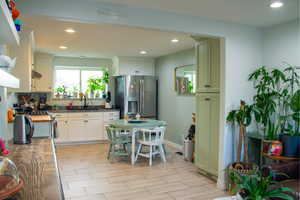 Kitchen with recessed lighting, stainless steel refrigerator with ice dispenser, wood finish floors, and plenty of natural light