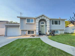 Bi-level home featuring driveway, stucco siding, and a garage