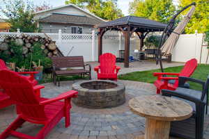 Fenced backyard featuring a patio, a gazebo, and a fire pit