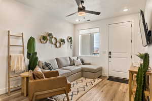 Living area with light wood-style flooring, a textured ceiling, and ceiling fan