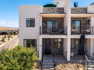 Contemporary house with stone siding, stucco siding, a mountain view, and a balcony