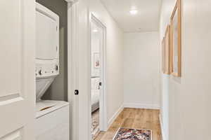 Laundry area with light wood finished floors and stacked washer and clothes dryer