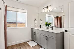 Full bath featuring double vanity, light wood-type flooring, recessed lighting, and curtained shower