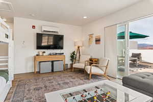 Living area with wood finished floors, an office area, recessed lighting, and a wall mounted air conditioner