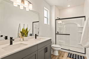 Bathroom featuring a stall shower, double vanity, and light wood-style floors