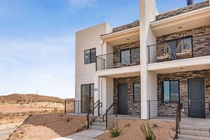 View of front of house with a balcony, stucco siding, and stone siding