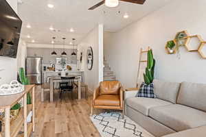 Living room featuring recessed lighting, a textured ceiling, light wood-type flooring, ceiling fan, and stairway