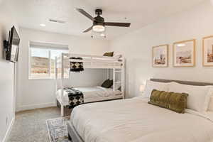 Bedroom featuring light carpet, a ceiling fan, and a textured ceiling