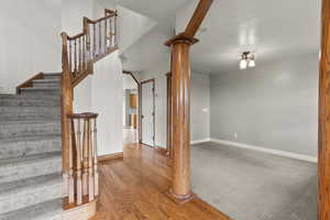 Staircase with wood finished floors, ornate columns, and carpet