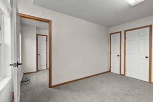 Unfurnished bedroom with carpet and a baseboard heating unit