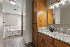 Bathroom featuring vanity, a bath, dark wood-type flooring, and a textured ceiling