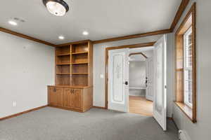 Unfurnished bedroom featuring ornamental molding, light carpet, recessed lighting, a baseboard heating unit, and arched walkways