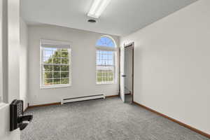 Unfurnished room featuring baseboard heating and carpet floors