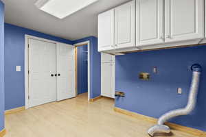 Laundry area with cabinet space, light wood finished floors, and hookup for a washing machine