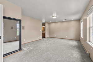 Spare room with baseboard heating, light carpet, and recessed lighting