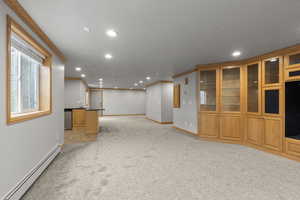 Unfurnished living room with baseboard heating, crown molding, light carpet, and recessed lighting