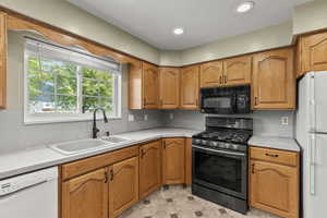 Kitchen with white appliances, light countertops, brown cabinetry, recessed lighting, and light tile patterned flooring