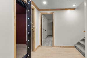 Corridor featuring light wood-style flooring, stairs, crown molding, and recessed lighting