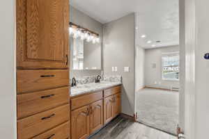 Full bathroom with double vanity, light wood finished floors, a baseboard heating unit, and recessed lighting